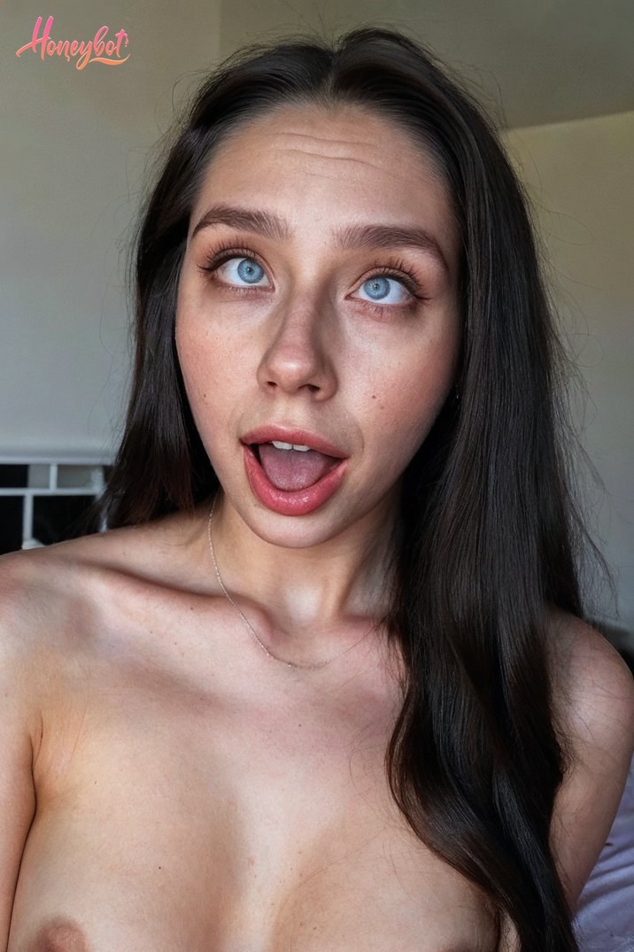 The image shows a woman with long dark hair. She appears to be shirtless, revealing her upper body. Her expression is exaggerated, with her mouth open and tongue sticking out. The…