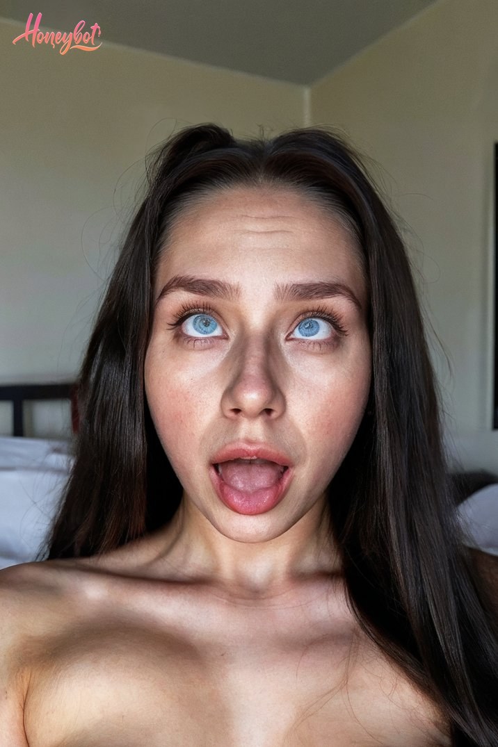 The woman in the picture has long dark hair and striking blue eyes. She appears to be making a playful facial expression, sticking out her tongue. The image shows her from the sho…